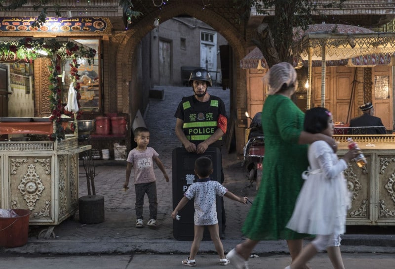 Uyghur children taunt a local police officer in Xinjiang.